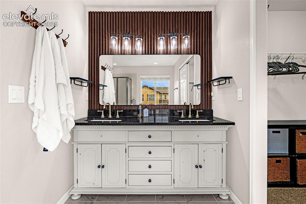 Image 22 of 35: Double vanity featuring a stone countertop, under-mount sinks with metallic