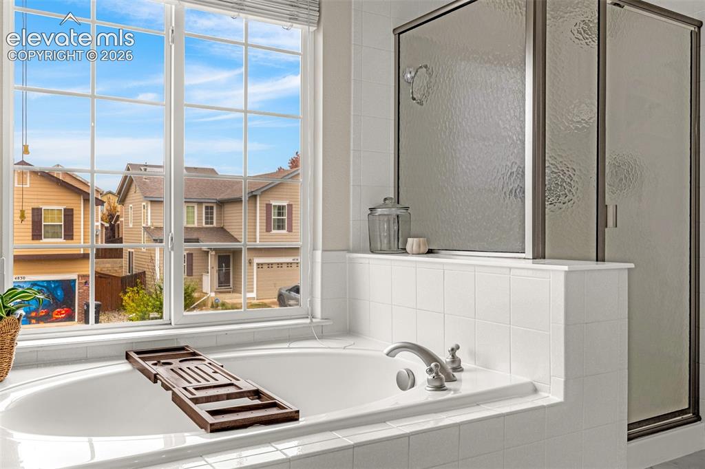 Image 23 of 35: Oversized soaking tub featuring a tiled surround, integrated shower with a