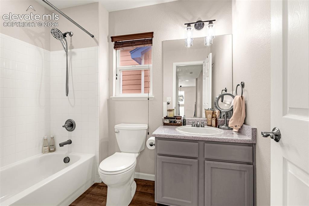 Image 24 of 35: Bathroom featuring a shower-tub combination with white tile surround, vanit