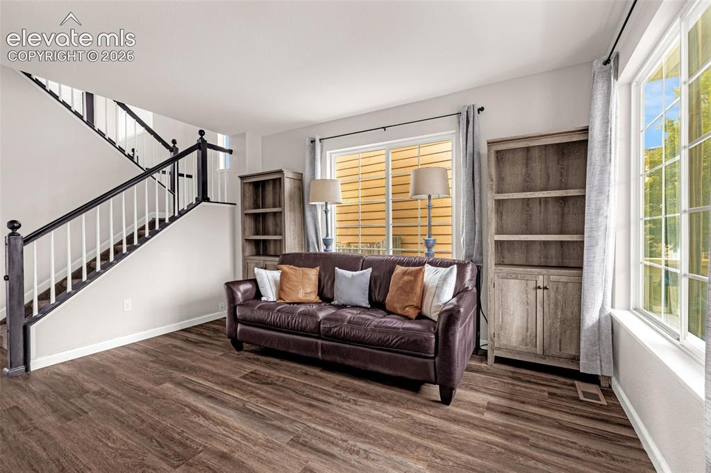 Image 4 of 35: Wood-finish flooring, staircase with a dark-finished handrail and white spi