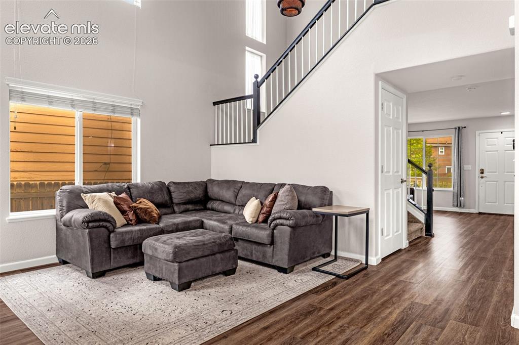 Image 5 of 35: High-ceilinged living area featuring wood-finish flooring, a staircase with
