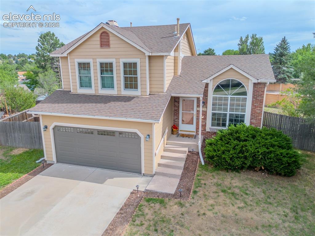 Image 1 of 31: Exterior featuring tan siding, brick accents, an arched window, a two-car g