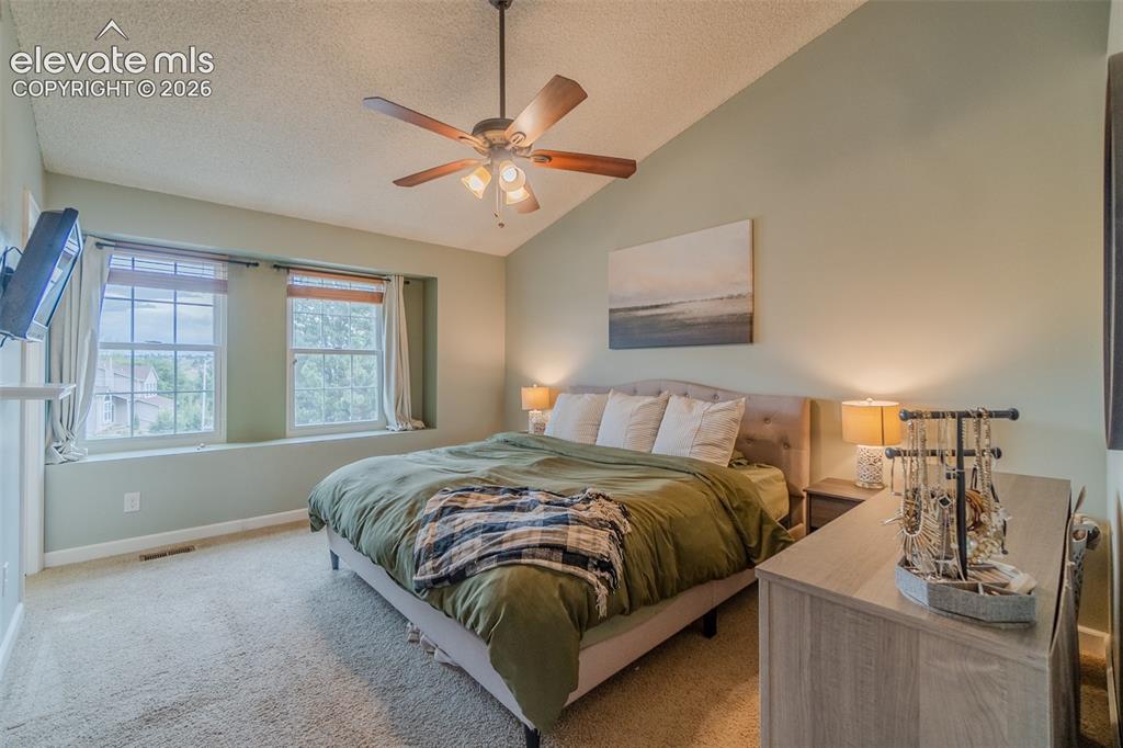 Image 12 of 31: Vaulted ceiling with a ceiling fan, new windows with window seat, and carpe