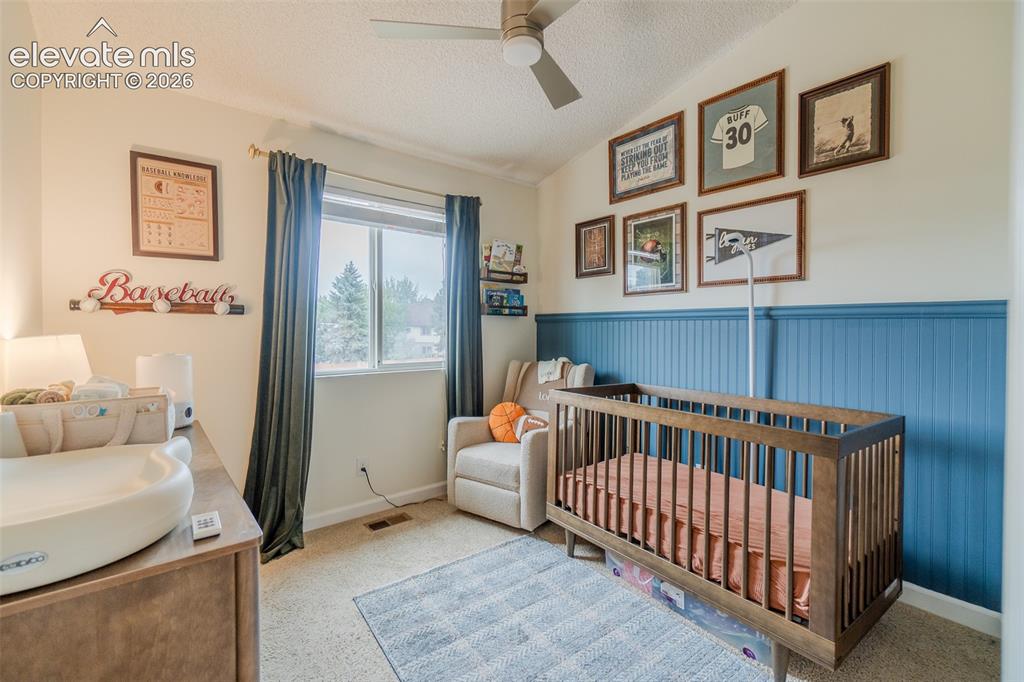 Image 15 of 31: Sloped ceiling with a ceiling fan, window with curtains, and two-tone wall 