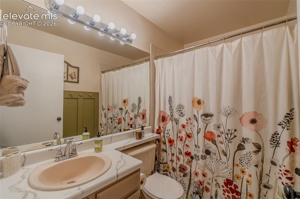Image 17 of 31: Vanity with integrated sink and chrome faucet, large wall mirror, and overh