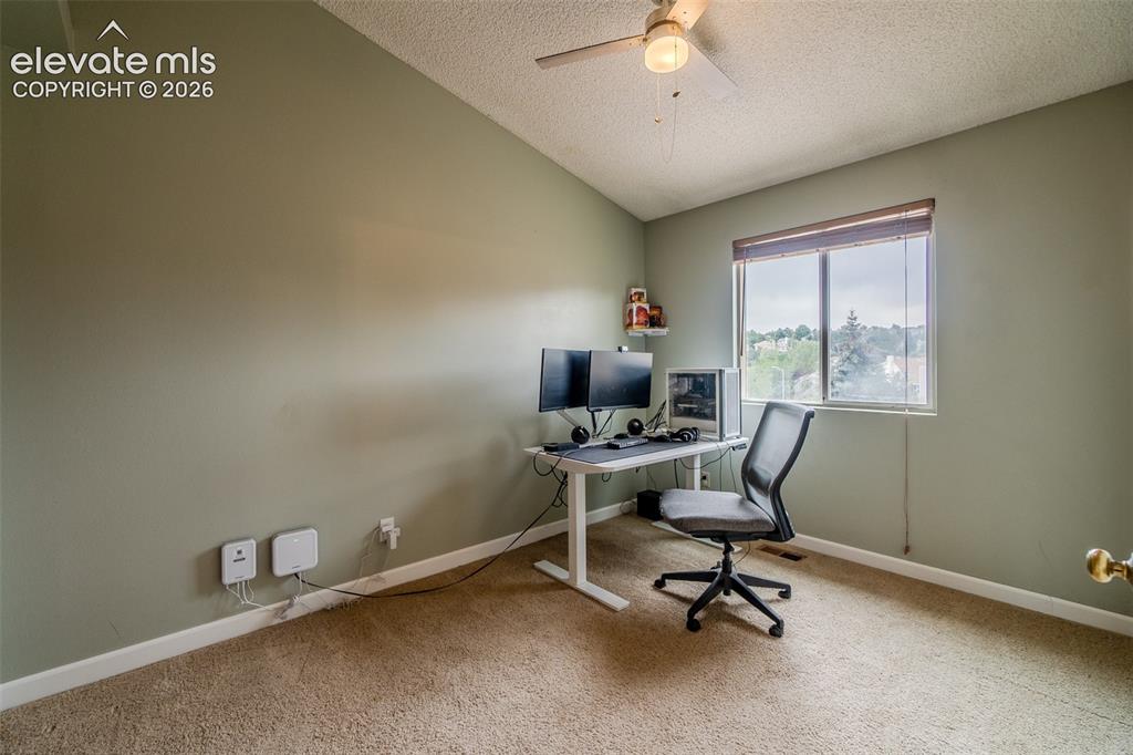 Image 19 of 31: Vaulted ceiling with a ceiling fan, neutral wall paint, window with blinds,