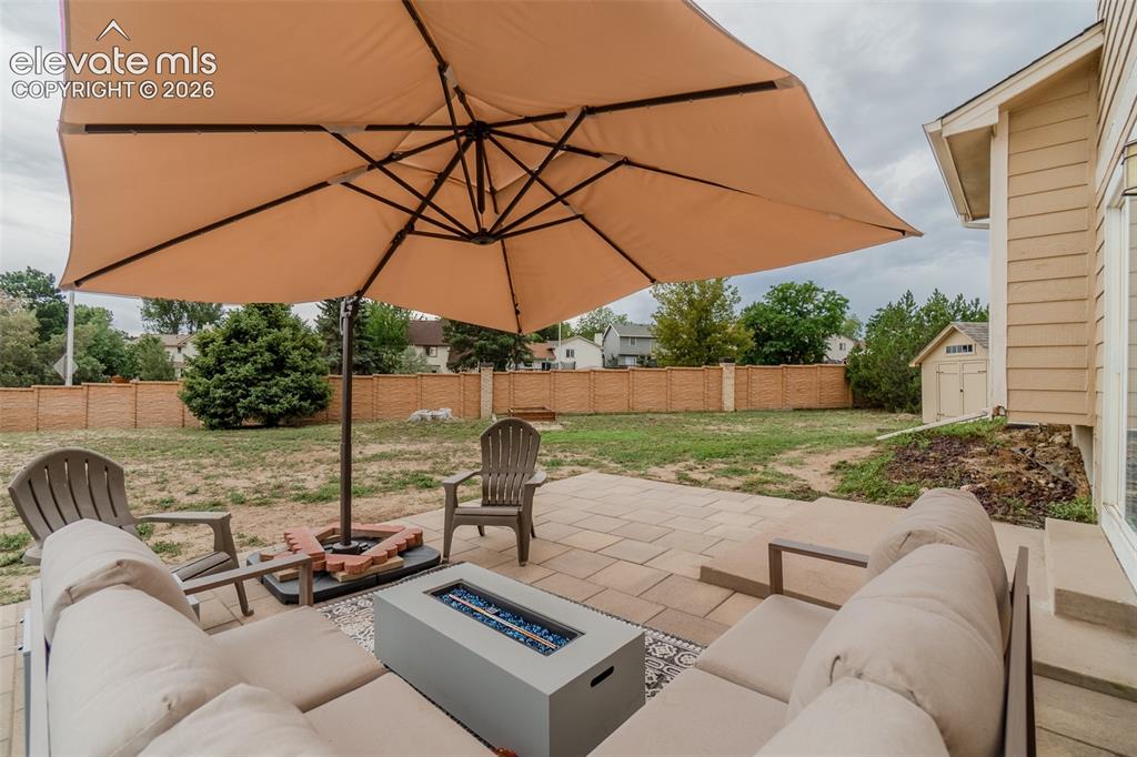 Image 20 of 31: Patio with pavers, a built-in fire pit, and a separate storage shed