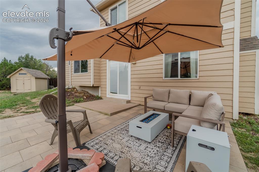 Image 21 of 31: Paved patio with a built-in fire pit, offering direct access to the interio