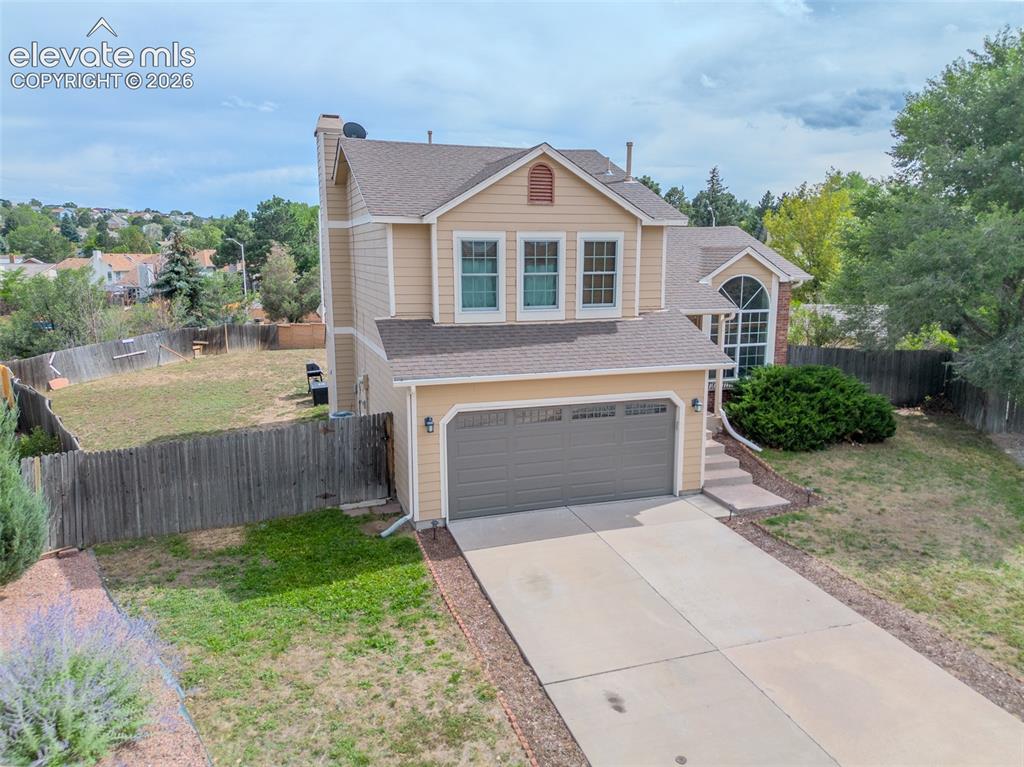 Image 27 of 31: Two-story residence with a two-car garage, multiple windows, and a fenced b