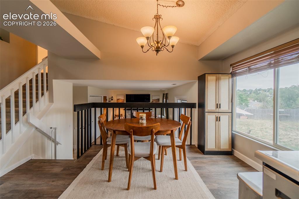 Image 5 of 31: Vaulted ceilings with a chandelier, wood-finish flooring, built-in cabinetr