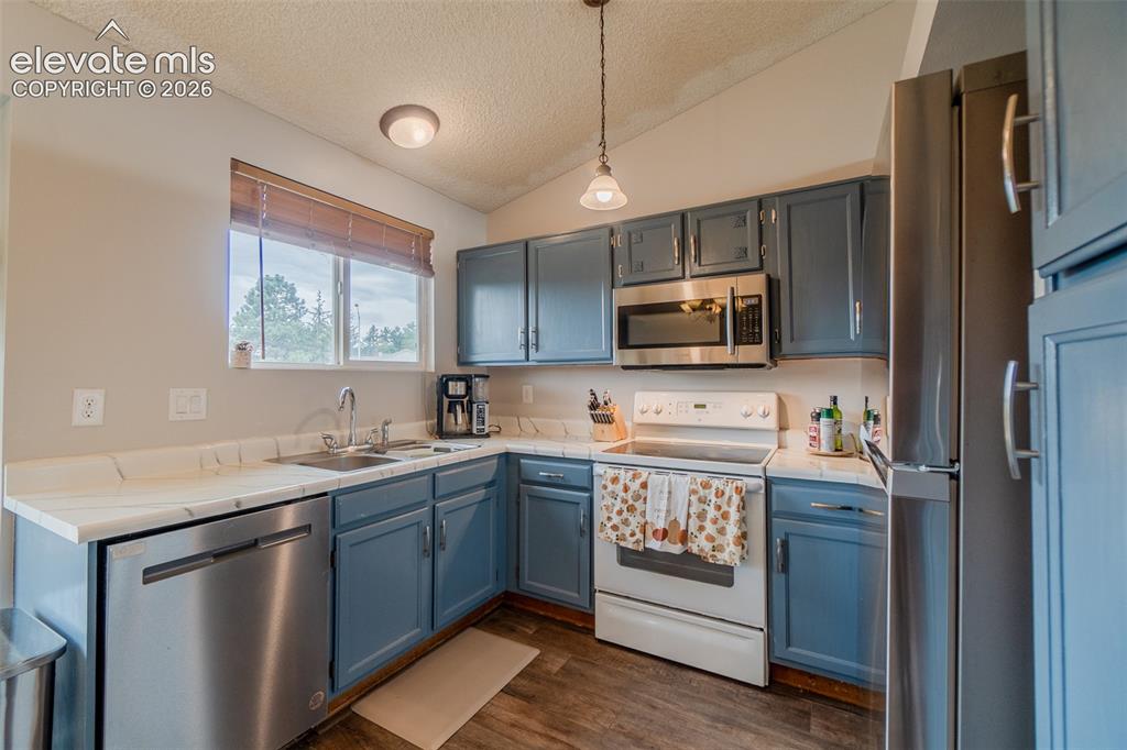 Image 7 of 31: Kitchen featuring blue cabinetry, white countertops, stainless steel dishwa