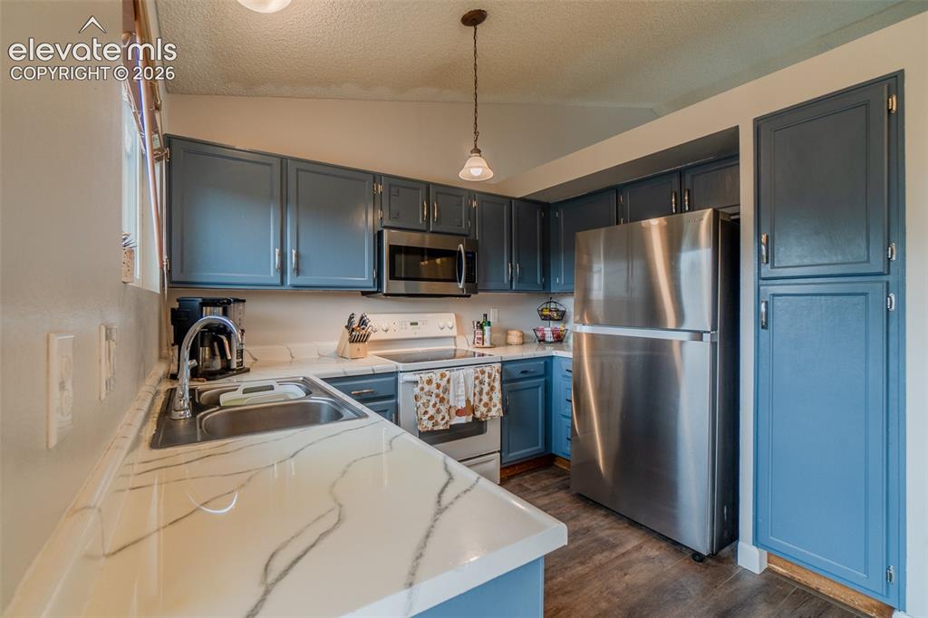 Image 8 of 31: Kitchen with blue cabinetry, pantry, white countertops with dark veining, s
