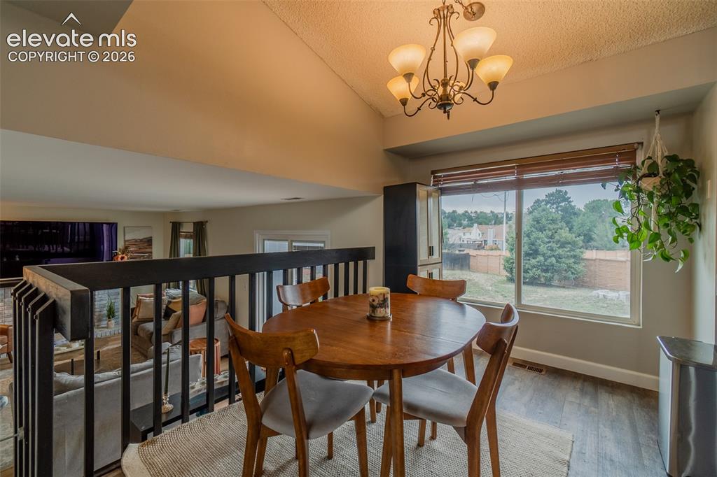 Image 9 of 31: Vaulted ceiling, wood-finish flooring, large window with blinds, railing ov