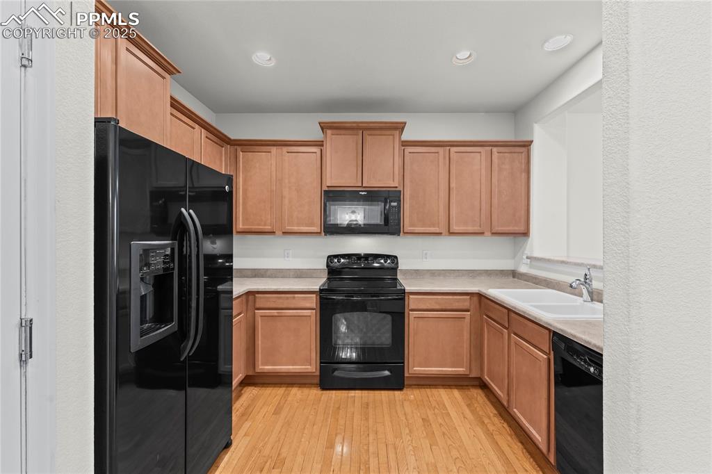 Image 10 of 26: Kitchen with black appliances, light countertops, light wood-style floors, 