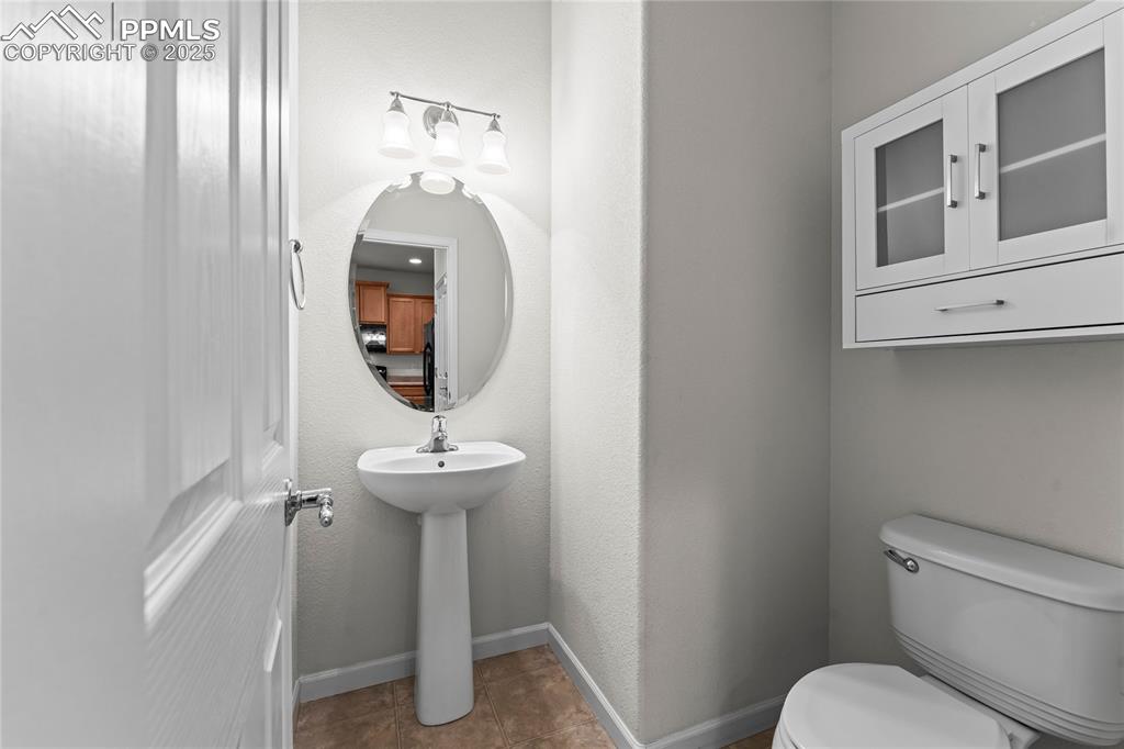 Image 12 of 26: Half bathroom featuring toilet and dark tile patterned flooring