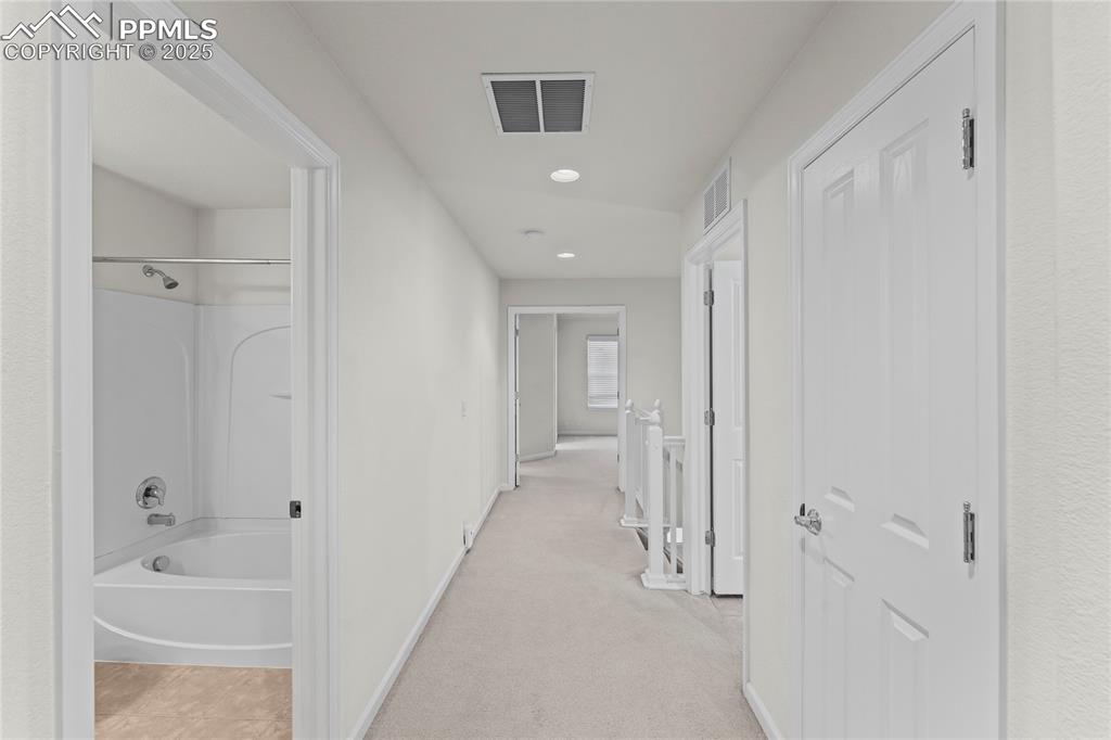 Image 14 of 26: Corridor with light carpet and recessed lighting
