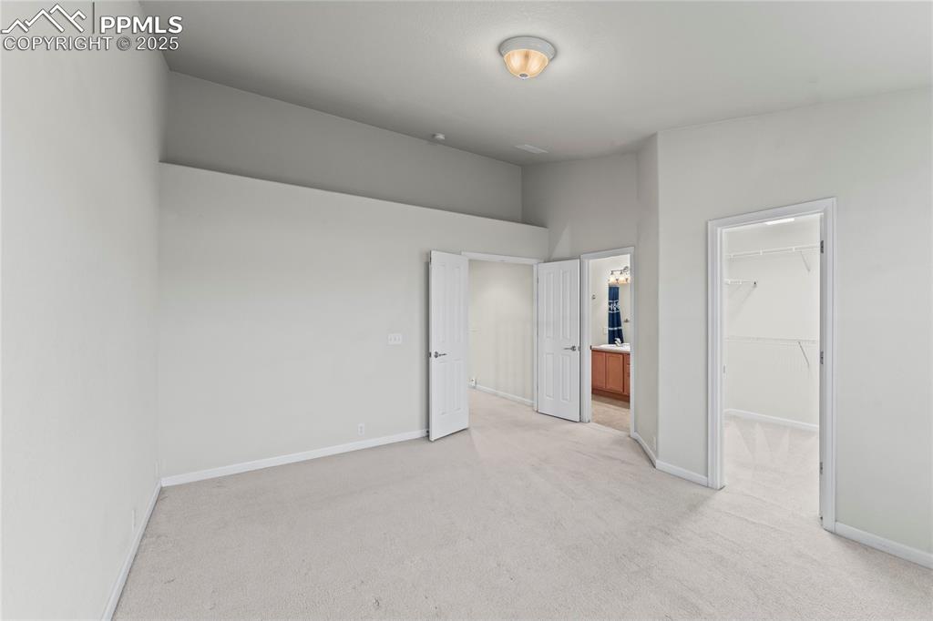 Image 17 of 26: Unfurnished bedroom with light colored carpet, a walk in closet, and connec