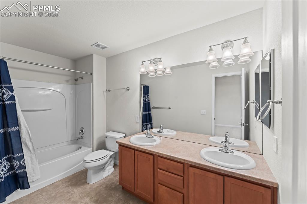 Image 19 of 26: Bathroom featuring double vanity, shower / bath combination with curtain, a
