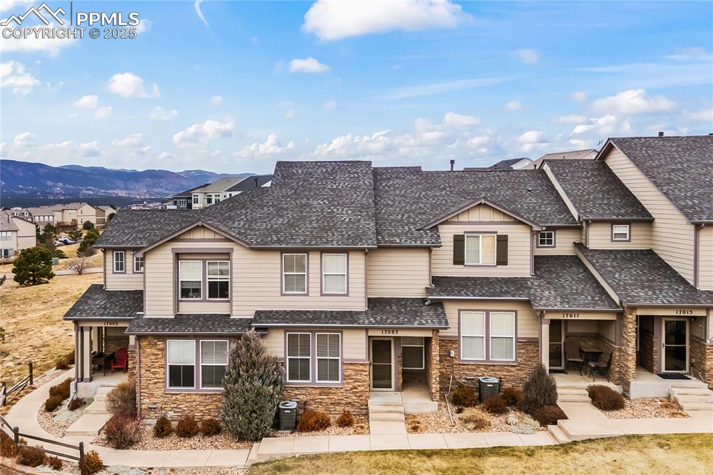 Image 2 of 26: View of front of house featuring stone siding, roof with shingles, and a po