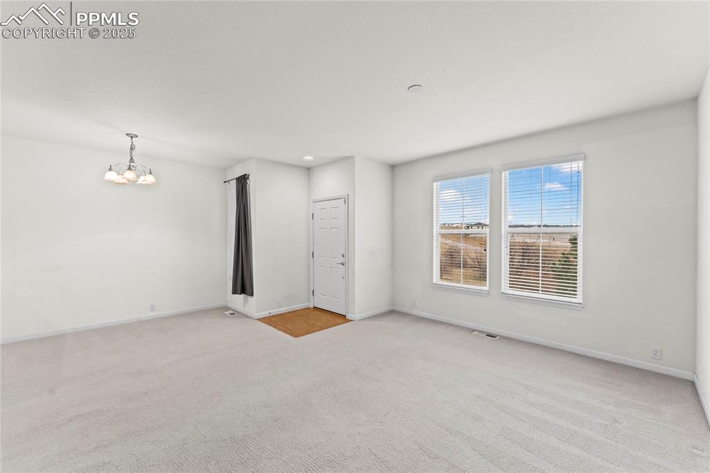 Image 8 of 26: Unfurnished room featuring light colored carpet and a chandelier