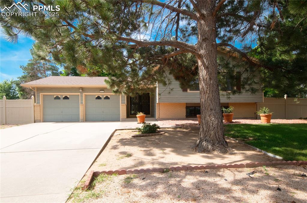 Caption: Split level home featuring brick siding, driveway, and a garage