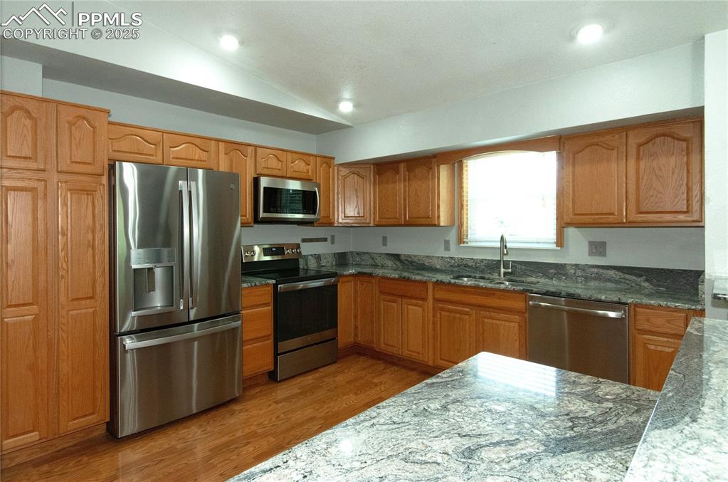 Image 10 of 42: Kitchen with stainless steel appliances, lofted ceiling, light wood-style f