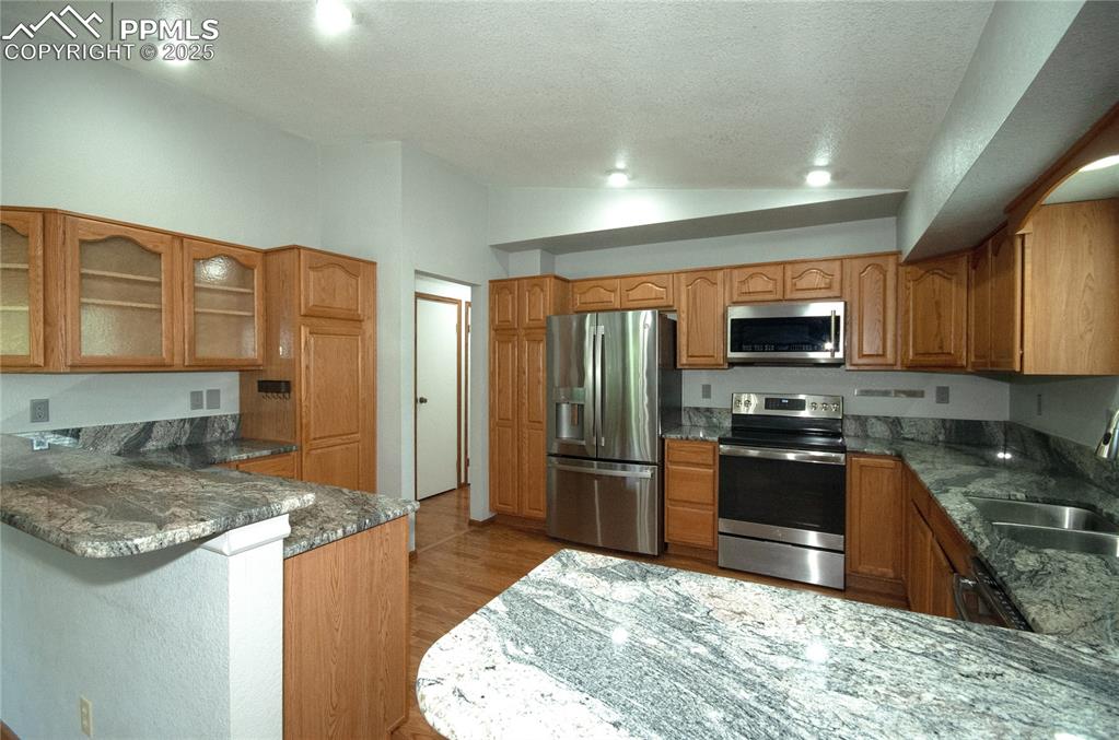Image 11 of 42: Kitchen featuring stainless steel appliances, a peninsula, glass insert cab