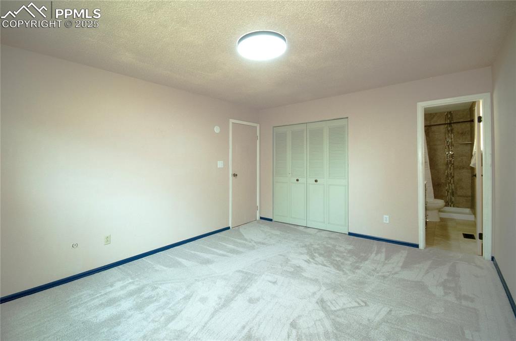 Image 14 of 42: Unfurnished bedroom with light carpet, a textured ceiling, a closet, and en