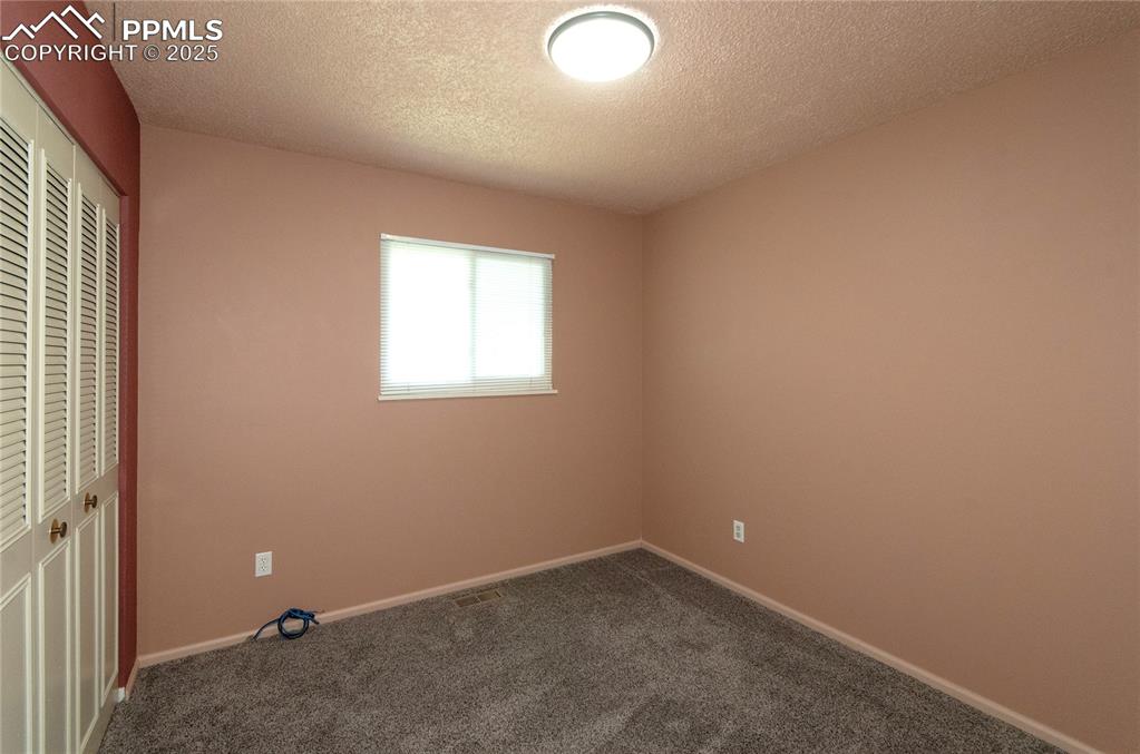 Image 15 of 42: Unfurnished bedroom featuring a textured ceiling, carpet floors, and a clos