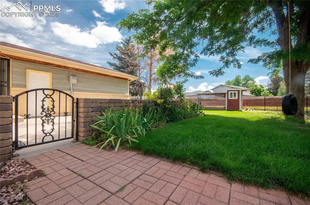 Image 26 of 42: Fenced backyard featuring a gate and a storage unit