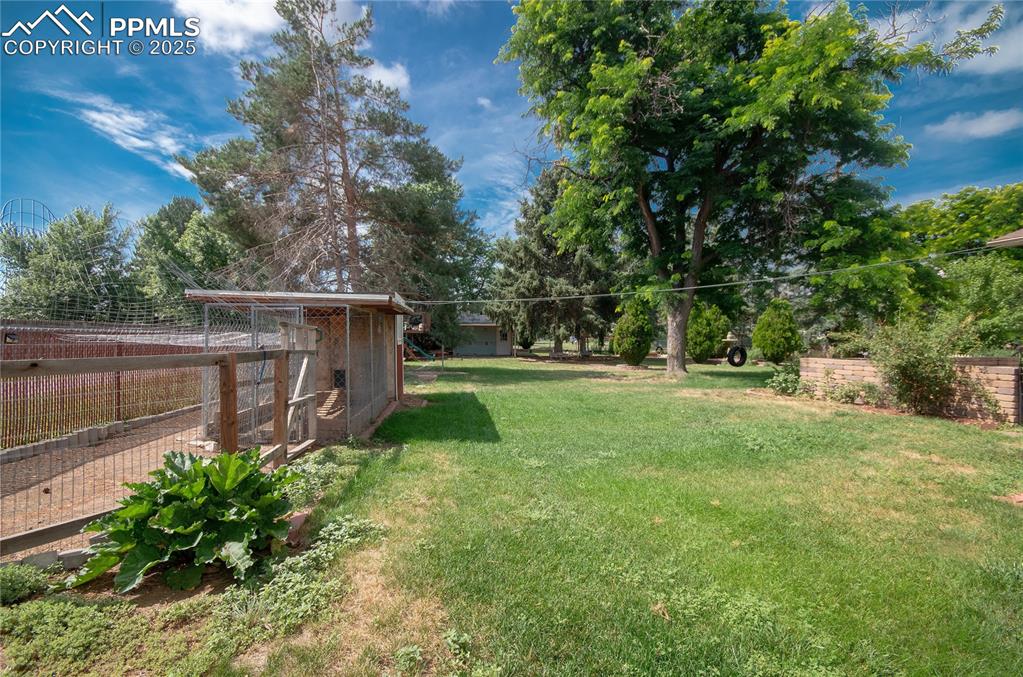 Image 32 of 42: View of yard with exterior structure, an outbuilding, and view of wooded ar