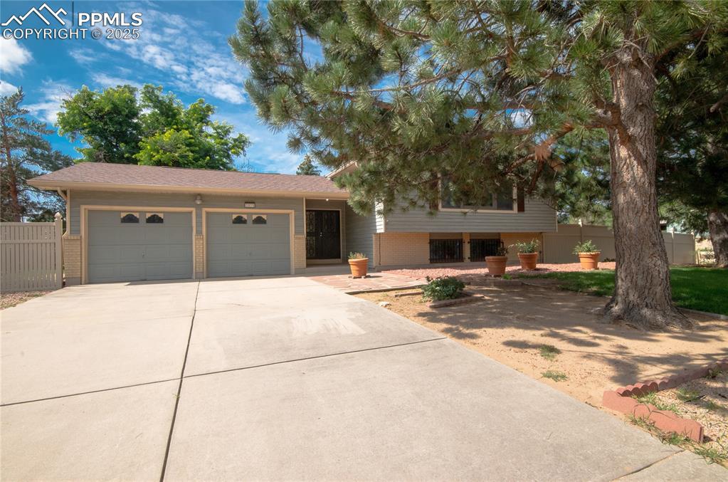 Image 4 of 42: Tri-level home featuring a garage, concrete driveway, and brick siding