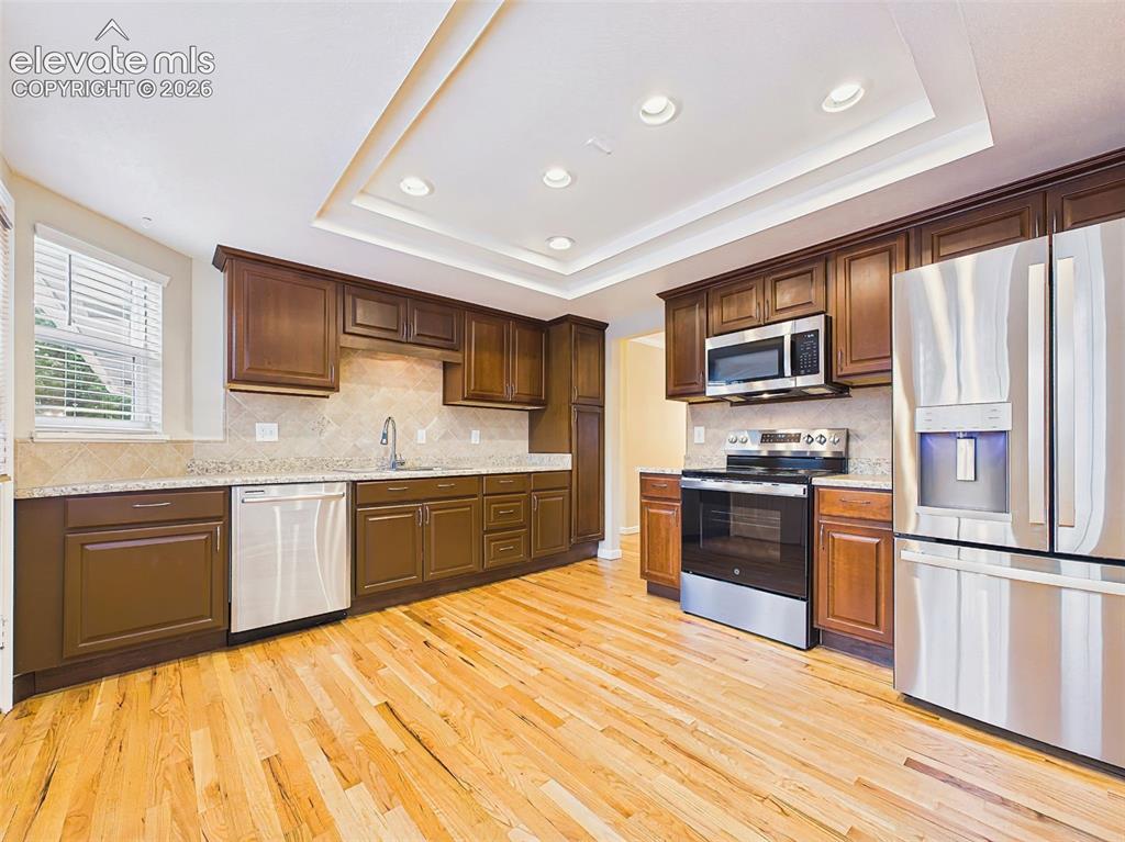 Image 10 of 50: Kitchen – Updated kitchen featuring rich wood cabinetry, stainless steel ap