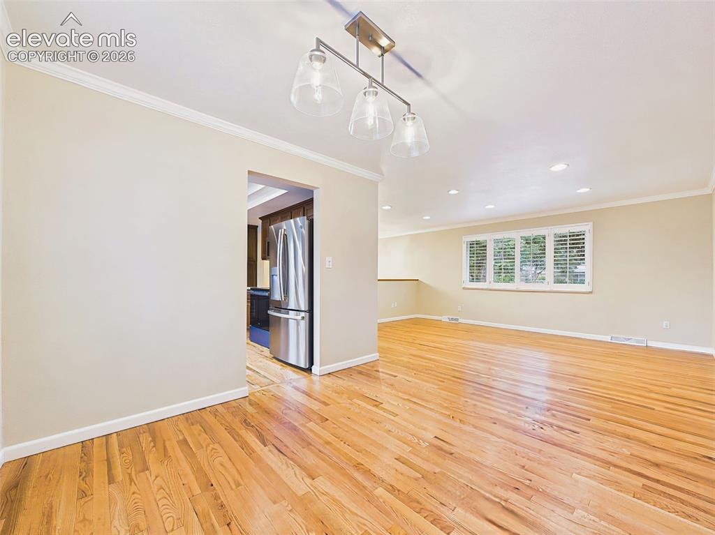 Image 17 of 50: Separate dining room with hardwood flooring, crown molding, and large windo