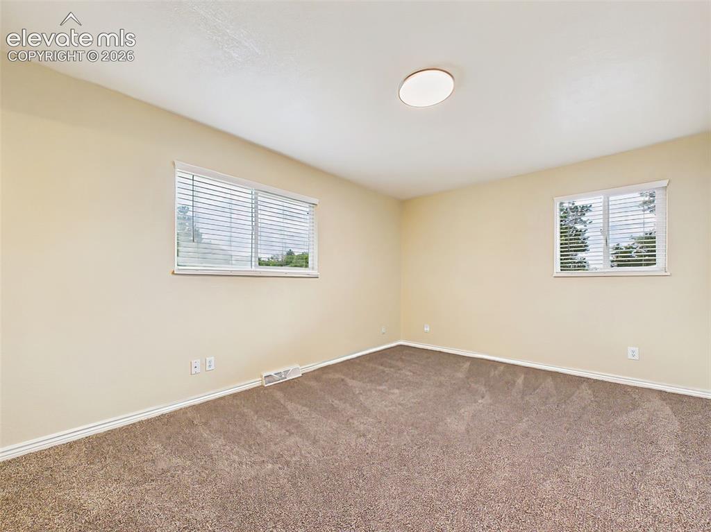 Image 21 of 50: Bright and inviting primary bedroom offering plush carpeting, multiple wind