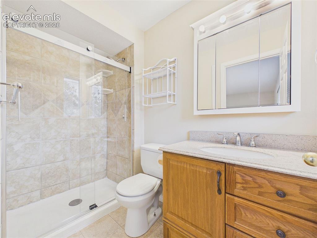 Image 23 of 50: The ensuite bath features a granite-topped vanity, updated lighting, and a 