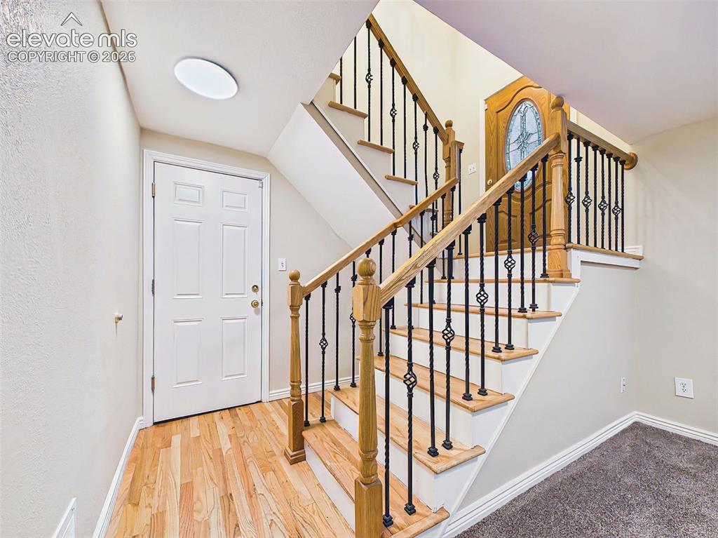 Image 29 of 50: Welcoming entryway featuring hardwood flooring and a staircase with wood tr