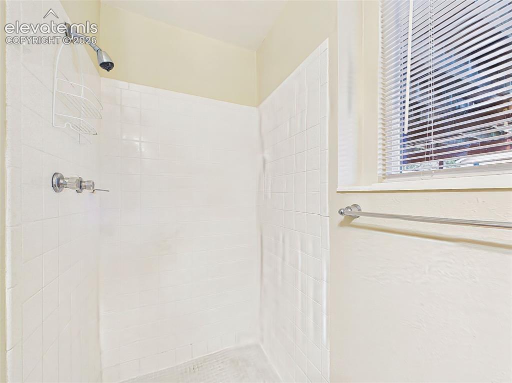 Image 38 of 50: Functional bathroom featuring a walk-in shower with tile surround and a win