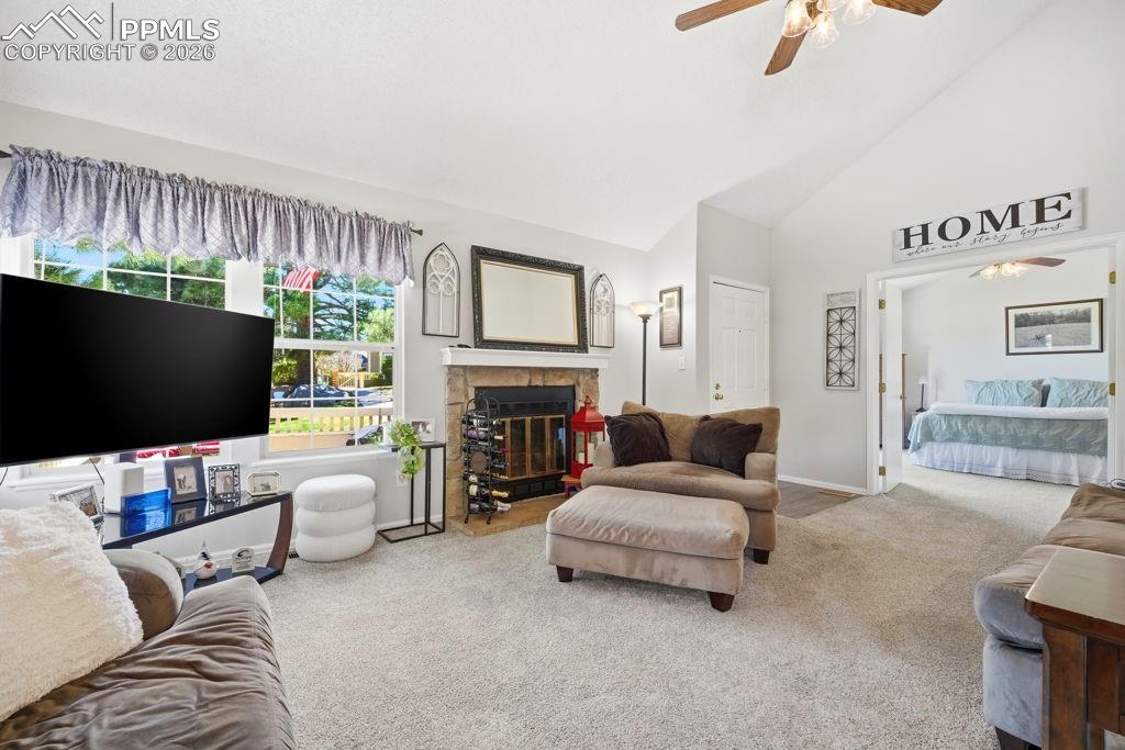 Image 13 of 41: Vaulted ceiling living room featuring a stone-surround fireplace with a man