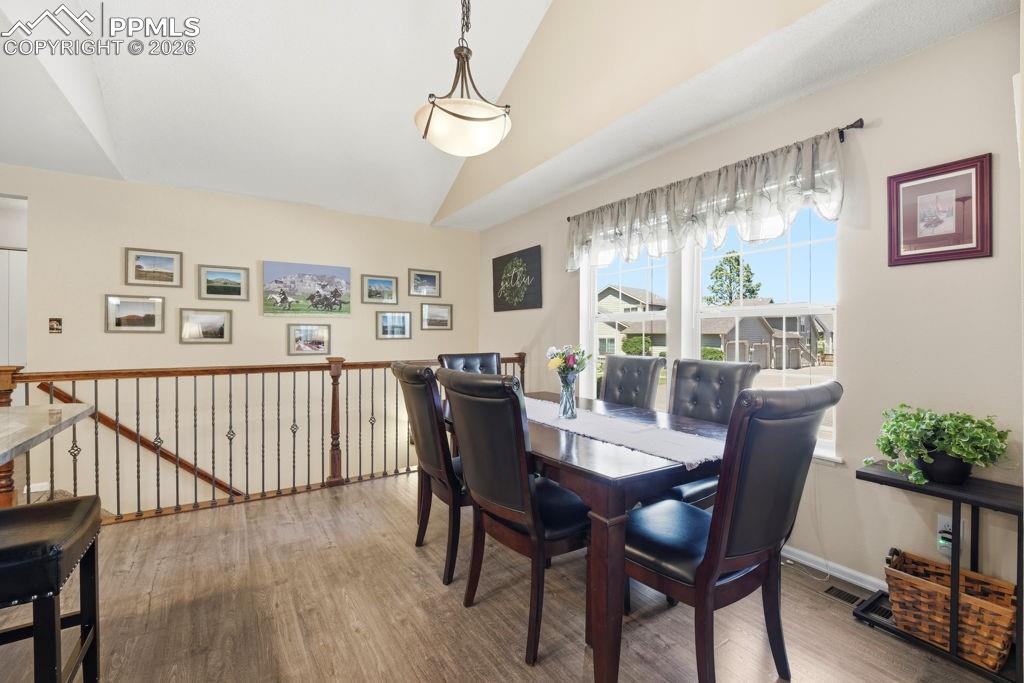 Image 14 of 41: Dining area featuring vaulted ceilings and wood-finish flooring.  Adjacent 