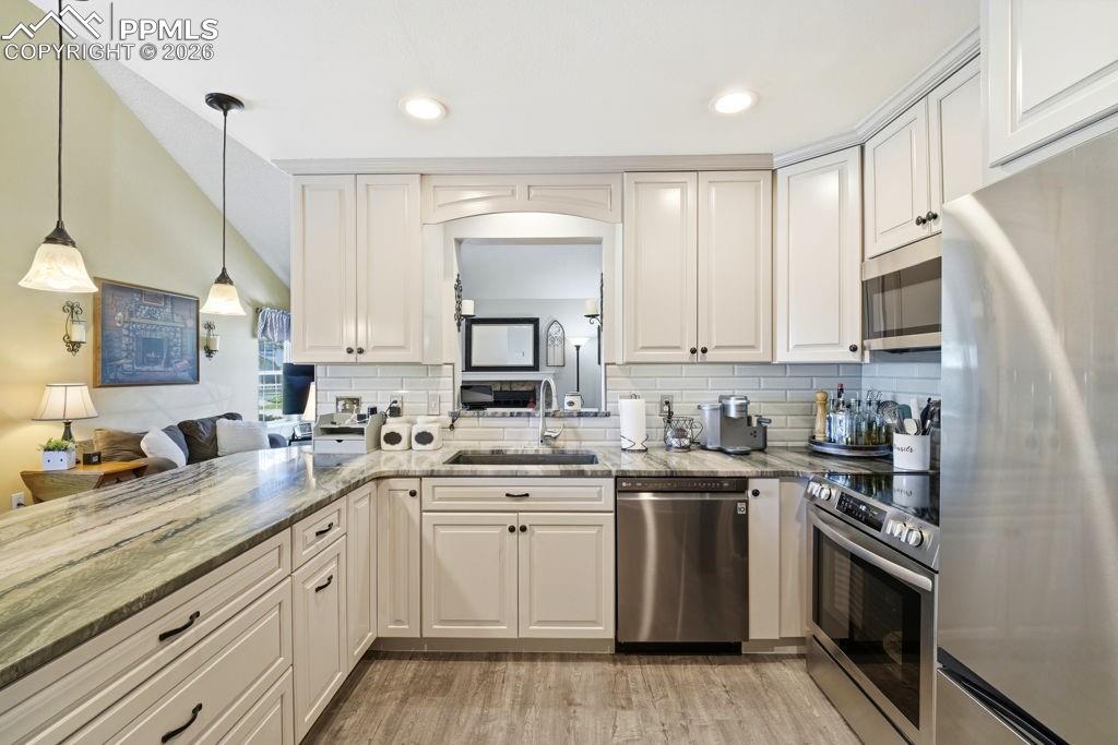 Image 19 of 41: Kitchen featuring white shaker cabinetry, stainless steel appliances, stone