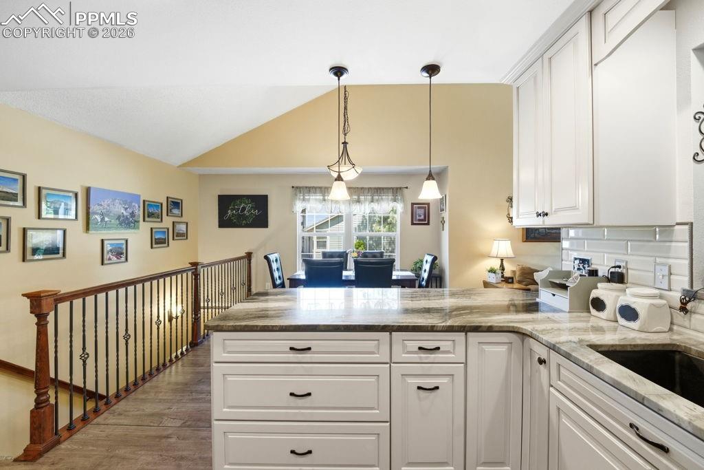 Image 20 of 41: Kitchen island with stone countertop, white cabinetry, and a black undermou