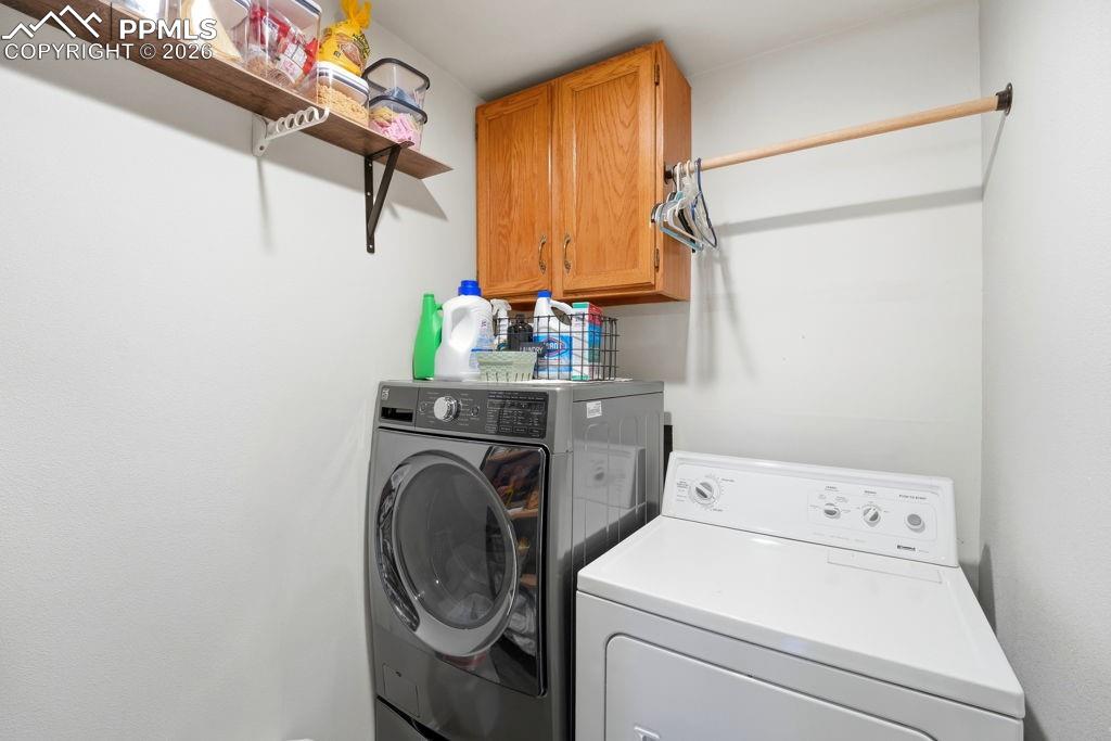 Image 21 of 41: Dedicated laundry area featuring a front-load washer, top-load dryer, and w
