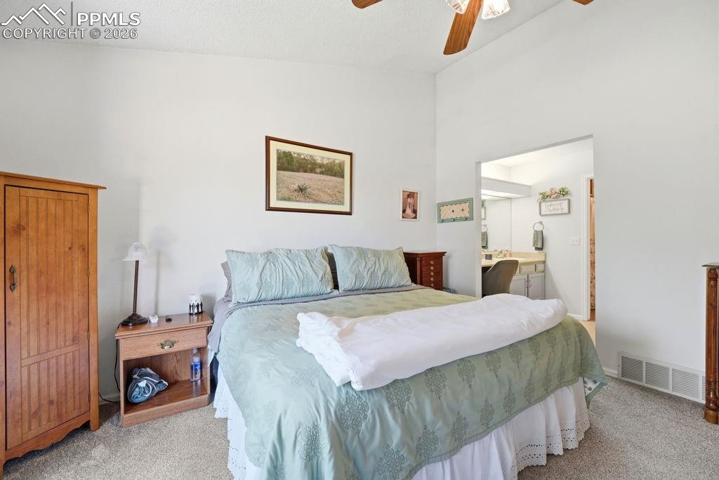Image 24 of 41: Carpeted bedroom featuring vaulted ceilings, a ceiling fan, and an open doo