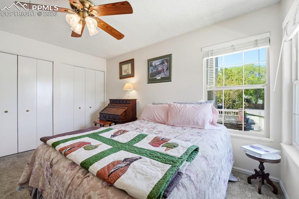 Image 28 of 41: Bedroom featuring a ceiling fan with light fixture, multiple bi-fold closet