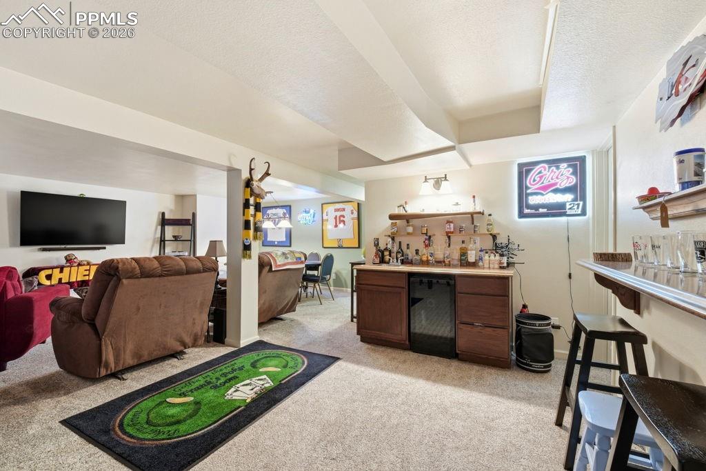 Image 32 of 41: Finished basement featuring a built-in dry bar with a compact refrigerator,