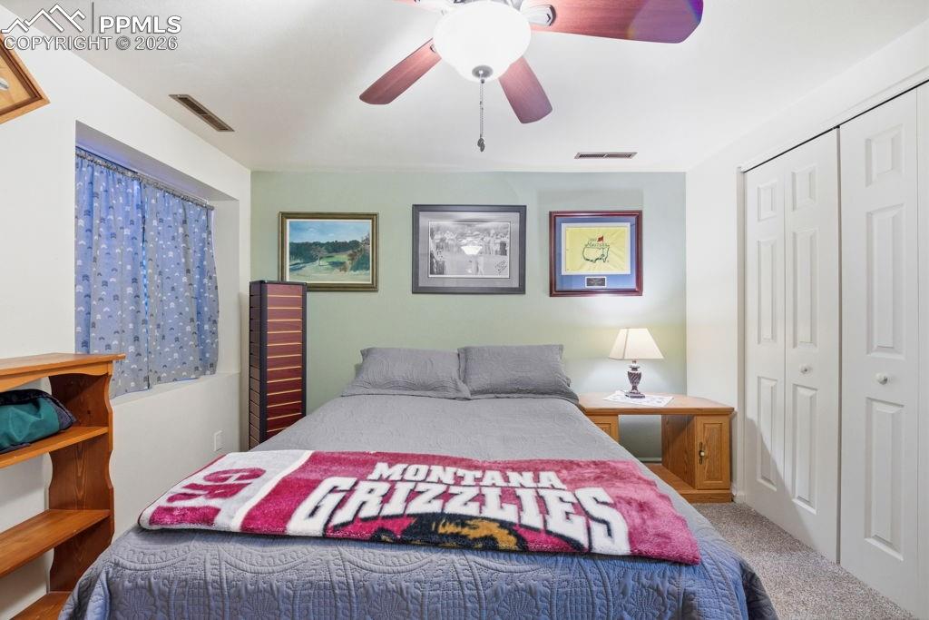Image 38 of 41: Lower level carpeted bedroom with a ceiling fan, light green accent wall, w