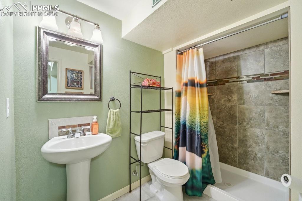 Image 40 of 41: Lower level tiled shower with decorative accent band and built-in shelving 