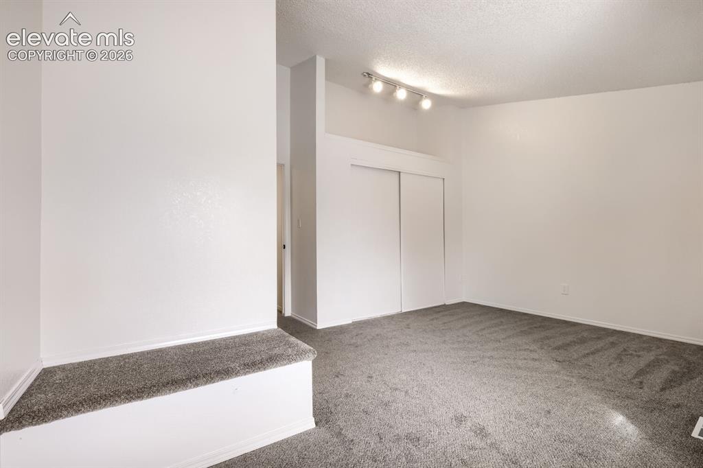 Image 12 of 25: Interior space featuring neutral-toned carpeting, a built-in elevated platf
