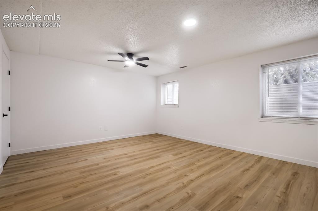 Image 17 of 25: Wood-finish flooring, dual windows, matte black ceiling fan with integrated